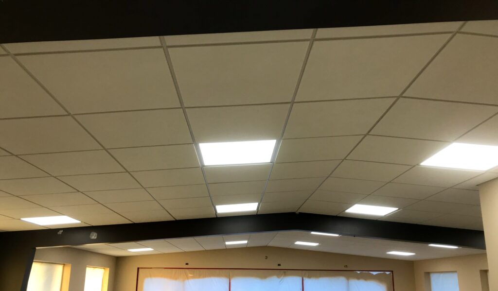 A ceiling with lights on in an office building.